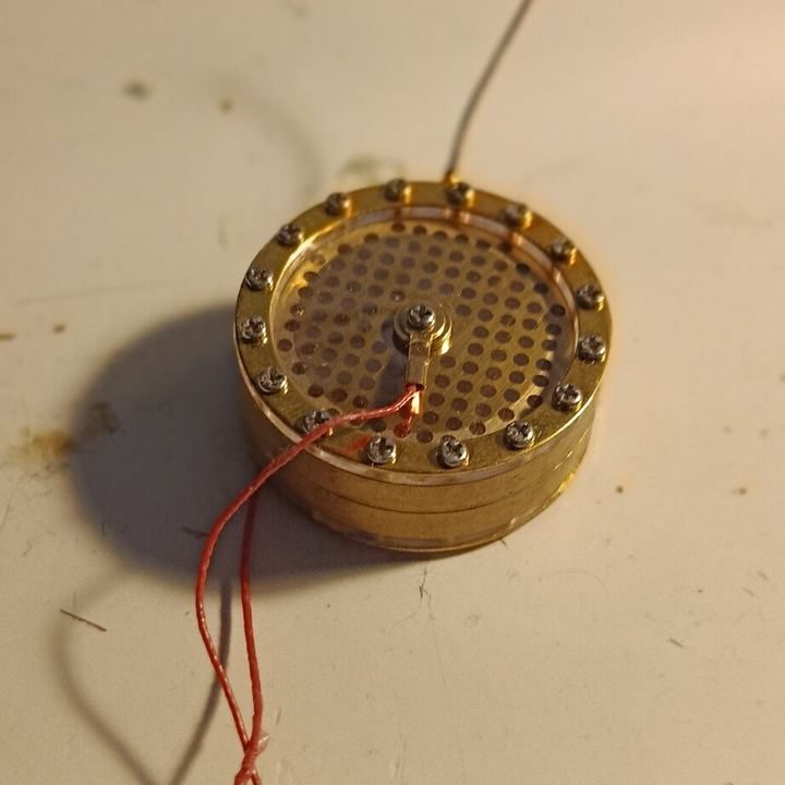 La capsule SC-600 seule, posée sur l’établi : bague dorée vissée, grille perforée, fil de connexion rouge.